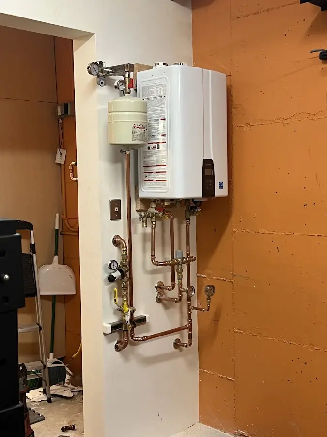 Plumbing technician inspecting water heater connections in Fort Collins